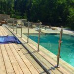 Glass pool fence installation near swimming pool with stainless steel posts.